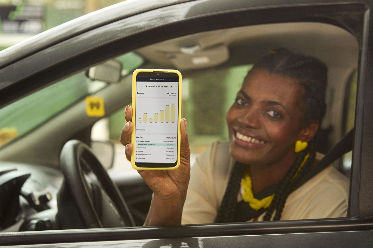 Motorista segura celular e mostra a tela com seus ganhos pelo aplicativo da 99- vale a pena ser motorista de aplicativo?